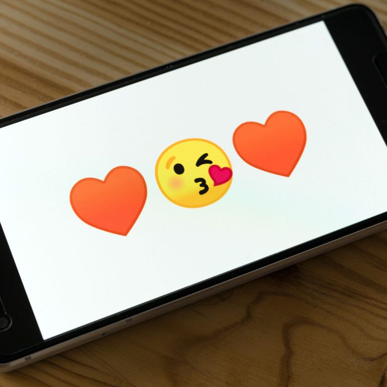 Emoticons of a heart, a kissing smile, and another heart displayed on a smartphone screen